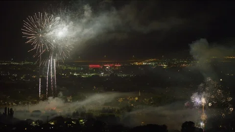 Wide shot of fireworks exploding in sky over cityscape at night / Pleasant Video stock 94436965