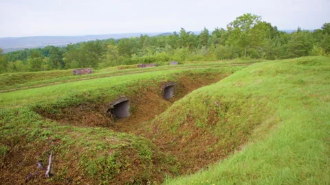Wide shot of a grassy field with two concrete bunkers Video stock 305106956