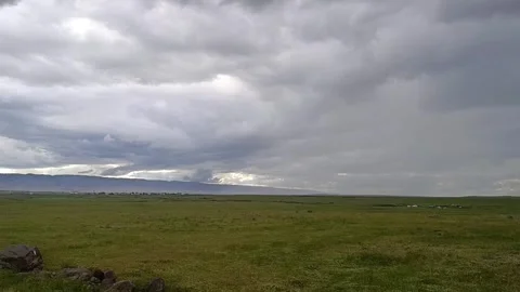 Wide Shot of Green Plain Under Overcast Sky with Distant Mountains 動画素材 335491163