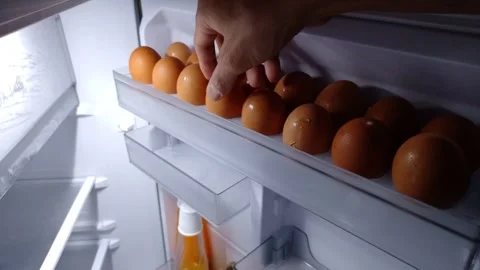 Wide shot of hand picks an egg from the refrigerator shelf Vidéo 332259828