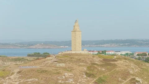Wide shot of the historic Torre de Hercules lighthouse standing on a rocky Stock Footage 346716006