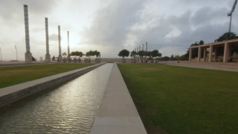 Wide shot of a huge square with a water basin, greenery and modern sculptures Stock Footage 221280105