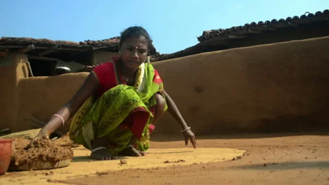 Wide shot of an Indian tribal woman smoothing floor with mud. Stock Footage