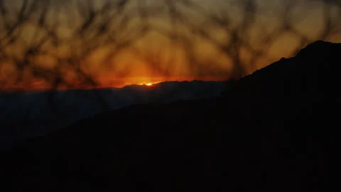 Wide shot landscape during sunset, with the sun setting behind dark mountain Video stock 282009943