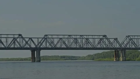 Wide shot of long freight train crossing massive steel railway bridge Stock Footage 337391056