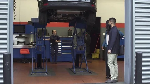 Wide shot of a mechanic talking to clients Stock Footage 76233096