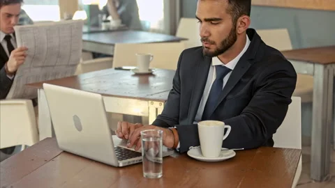 Wide shot of middle eastern business man typing on his laptop and drinking coffe Stock Footage 199633944
