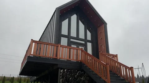 A wide shot of a modern, sleek, two-story cabin or modular home Stock Footage 320516355