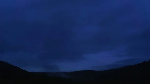 Wide shot of mountain forest under time lapse grey clouds floating by at dawn Stock Footage 75868416