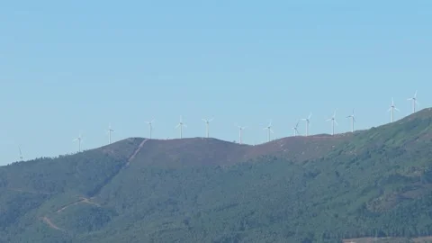 Wide shot of multiple wind turbines lined up along a mountain ridge, surrounded Stock Footage 346705902