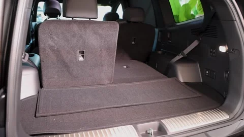 Wide shot of open trunk cargo space in modern SUV EV car showing folded Stock-Footage 347097045