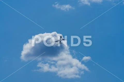 Wide shot photo looking up to the sky of a commercial airline jet flying over Stock Photos