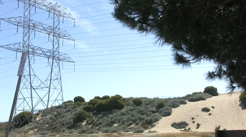 Wide Shot of Power Lines &amp; Tower with Field &amp; Sand Dune Below Stock Footage 4279869