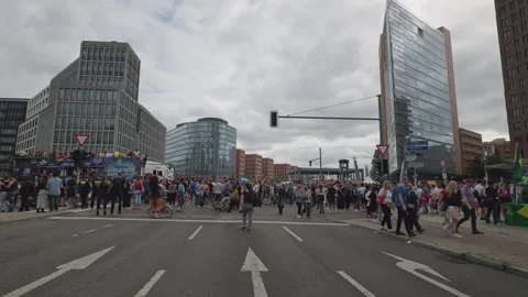 Wide shot of Pride parade crowd gathered at Potsdamer Platz with modern Stock Footage 346240531