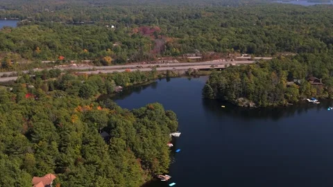 Wide shot pulling bac of lake and forest.  Highway in middle of shot Stock Footage 251565048