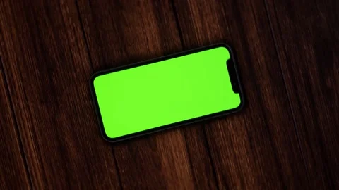 A Wide shot pushing in while rotating around cell phone displaying green screen Video stock 155223867