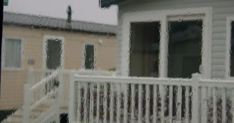Wide Shot of rain on a static caravan window with static caravans Porch in Stock Footage 346814605