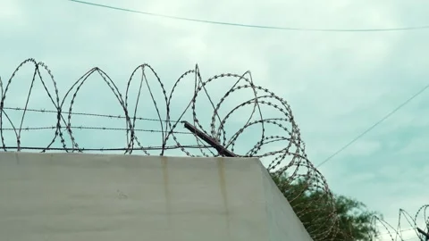 Wide shot of razor wire on a wall with subtle background elements. Stock Footage 323460925