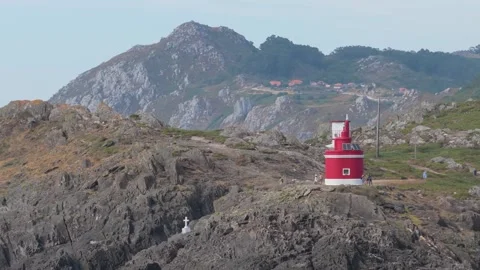Wide shot of the red and white Faro de Punta Robaleira lighthouse situated on a Stock Footage 346718033