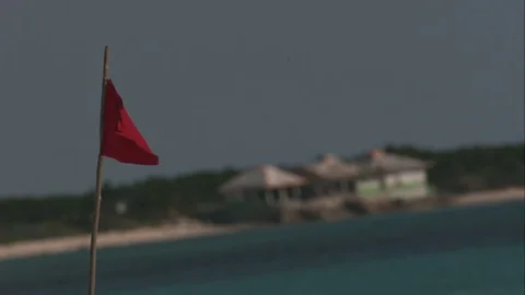 Wide Shot of Red Flag Waving in Slow Motion over Beach in Cozumel, Mexico Stock Footage 82879584