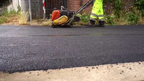 Wide Shot of Road Worker Using Vibrating Asphalt Compactor – 4K Stock Footage 311072986
