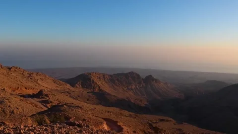 A wide shot of a rugged mountain range in Oman, bathed in the warm, golden Stock Footage 318648298