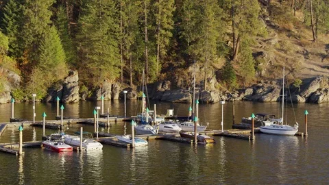 Wide shot of sailboats at dock on shimmering lake / Coeur d'Alene, Idaho Stock Footage