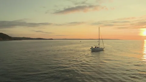 Wide shot sailing boat setting off into dawn sun, Mevagissey, Cornwall UK Stock Footage 73912427