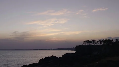 WIDE SHOT OF SILHOUETTED CLIFFS AND OCEAN AT SUNSET Stock Footage