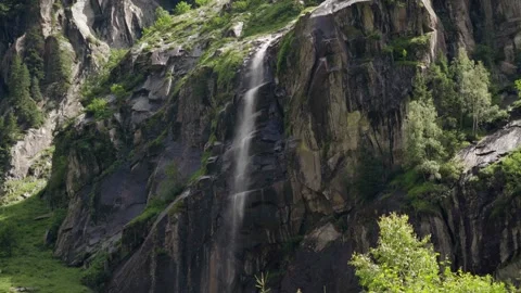 Wide shot of a small waterfall makes it's way through the mountains Stock Footage 283564922