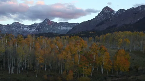 Wide shot of sunset clouds over snowy mountains and colorful Autumn trees Video stock 68442482