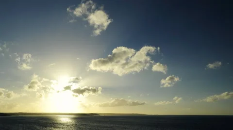 Wide shot of a sunset in timelapse over the ocean and cliffs on the horizon. Stock Footage 68765529