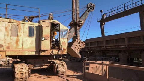 Wide shot of train consisting of dump cars slowly moving. Excavator approaches Stock Footage 75393220