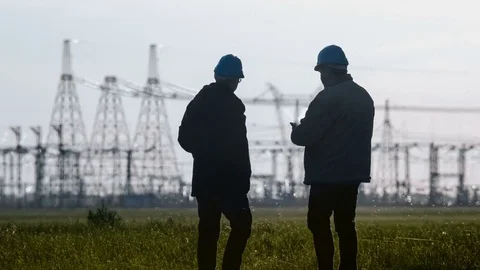 Wide shot of two engineers in hard hat discussing something talking on a Stockbeeldmateriaal 75632031