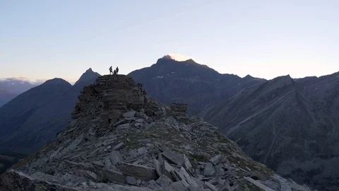 Wide shot of two men on mountain peak raising hands up, 4K Stock Footage 129611251