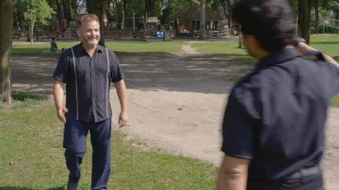 Wide shot - Two men shake hands in a park - shot on RED Stock Footage 124716596