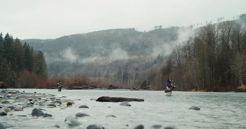 Wide shot of two people fly fishing on a river in the Pacific Northwest Stock Footage 102187749