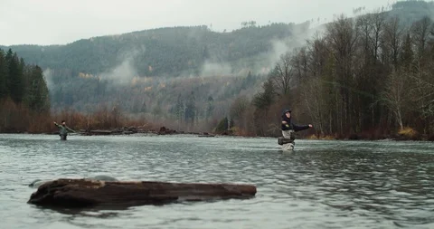 Wide shot of two people fly fishing on a river in the Pacific Northwest Stock Footage 102187780