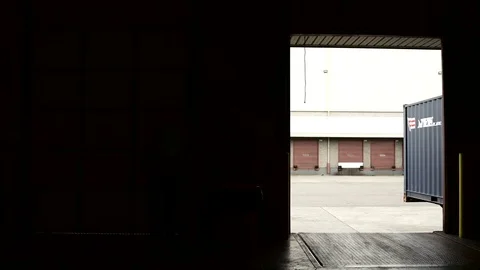 Wide shot of a warehouse worker rolling up a door Stock-Footage 76535035
