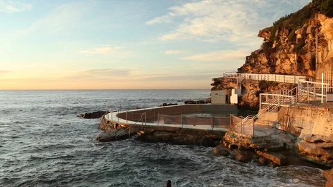 Wide shot of waves crashing into empty rock pool at sunrise Stock Footage 90937353
