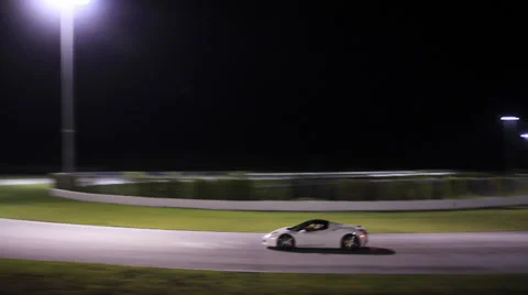 Wide shot of white Ferrari on track turning corner Stock Footage