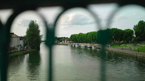 Wide shot of Yonne River with trees and bridge barriers foreground, Sens, France Stock Footage 339201450