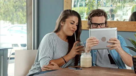 Wide shot of young couple using digital tablet computer in cafe. Stock Footage 199634726