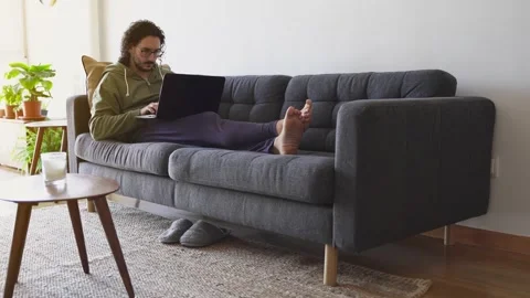 Wide shot of young man using laptop on the sofa Stock Footage 164904981
