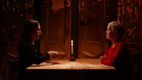 Wide side shot of enigmatic fortune teller reading tarot cards to middle-aged Stock Footage 274456473