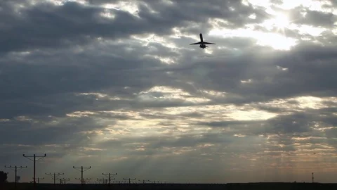 Wide of a silhouetted airplane taking off in front of a sunrise cloudscape Stock Footage 80439911