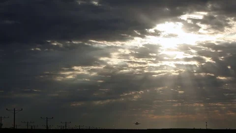 Wide of a silhouetted airplane taking off in front of a sunrise cloudscape Stock Footage 80490460
