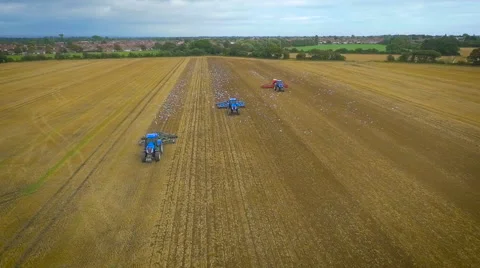 Wide slow motion aerial drone footage of tractors ploughing fields Stock Footage 59864608