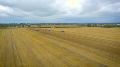 Wide slow motion aerial drone footage of tractors ploughing fields Stock Footage 61741222