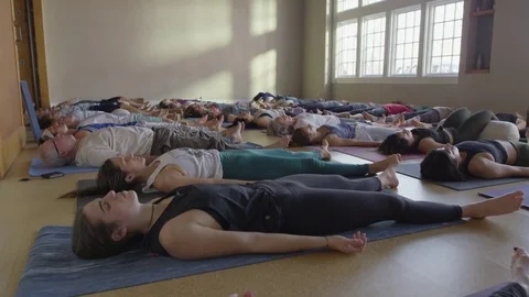 Wide slow motion high angle shot of yoga students in corpse pose / Provo, Utah, Stock Footage 77998305
